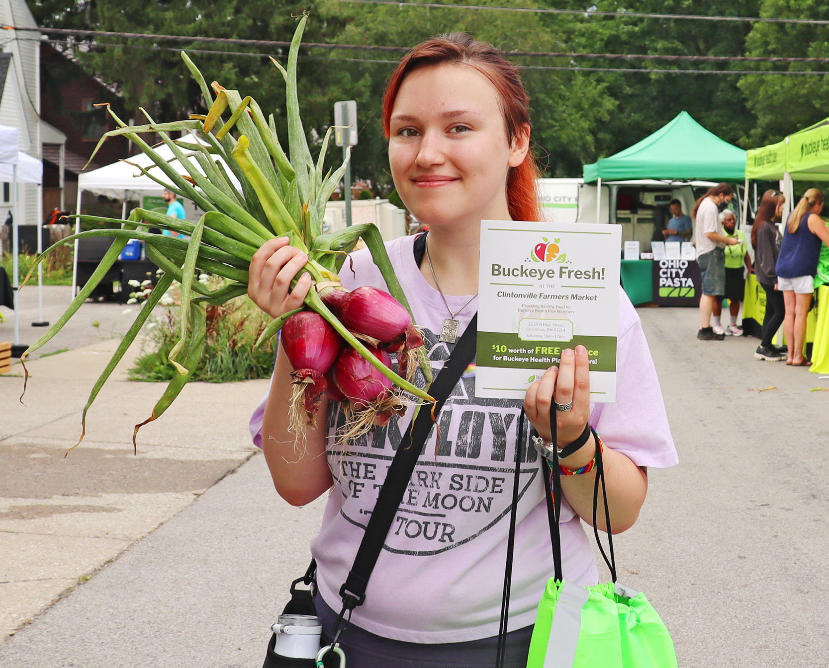 A woman holds fresh produce at the farmers market.