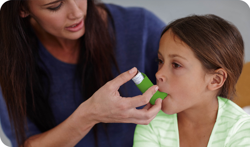 A women helps a child with her inhaler.