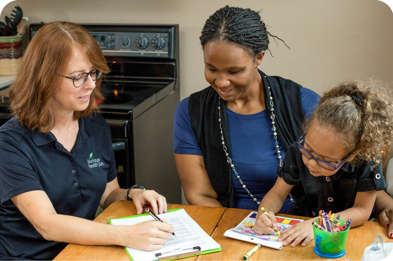 A Buckeye representative helps a woman with her care plan while her child colors. 