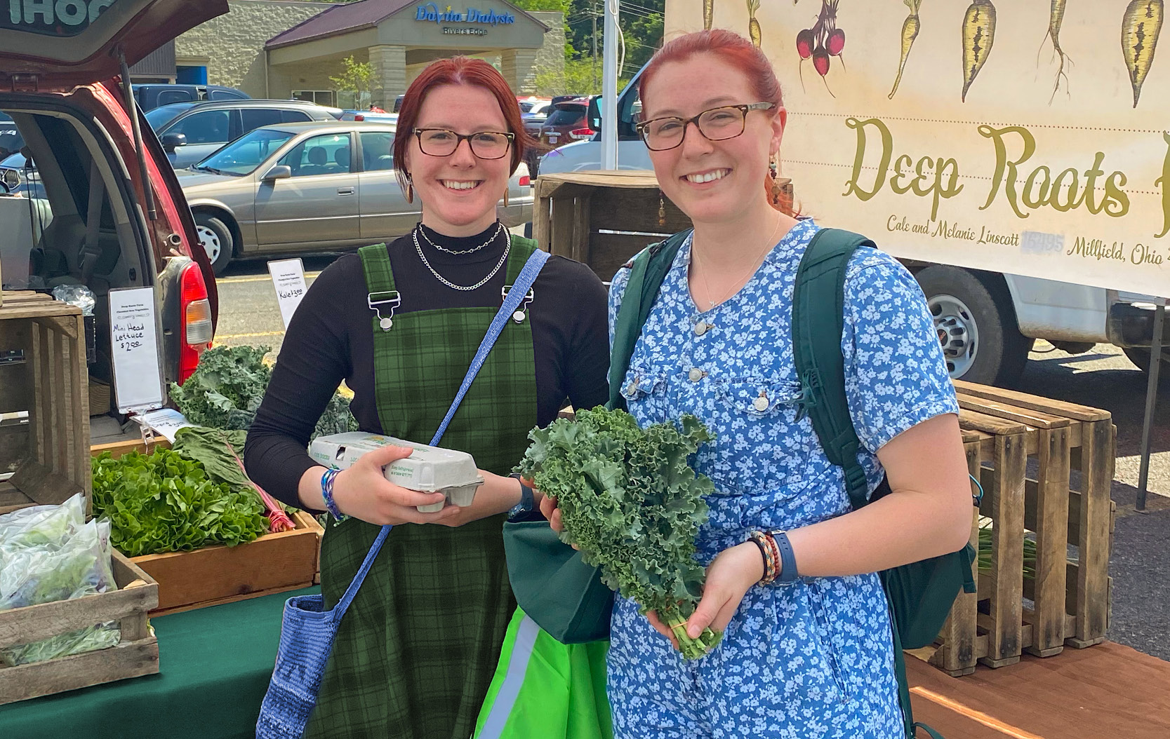 Buckeye Members hold up fresh produce at Buckeye Fresh Farmers Market