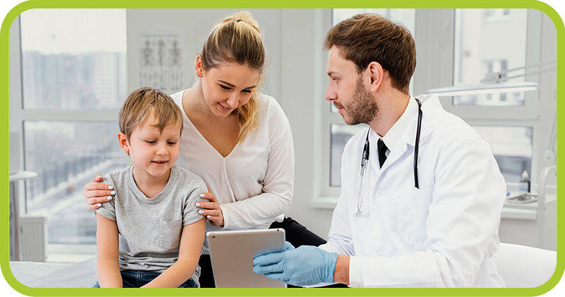 Male doctor shows a mother and her young son information on a computer tablet. 