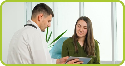 A male doctor reviews notes on a tablet with a femal patient