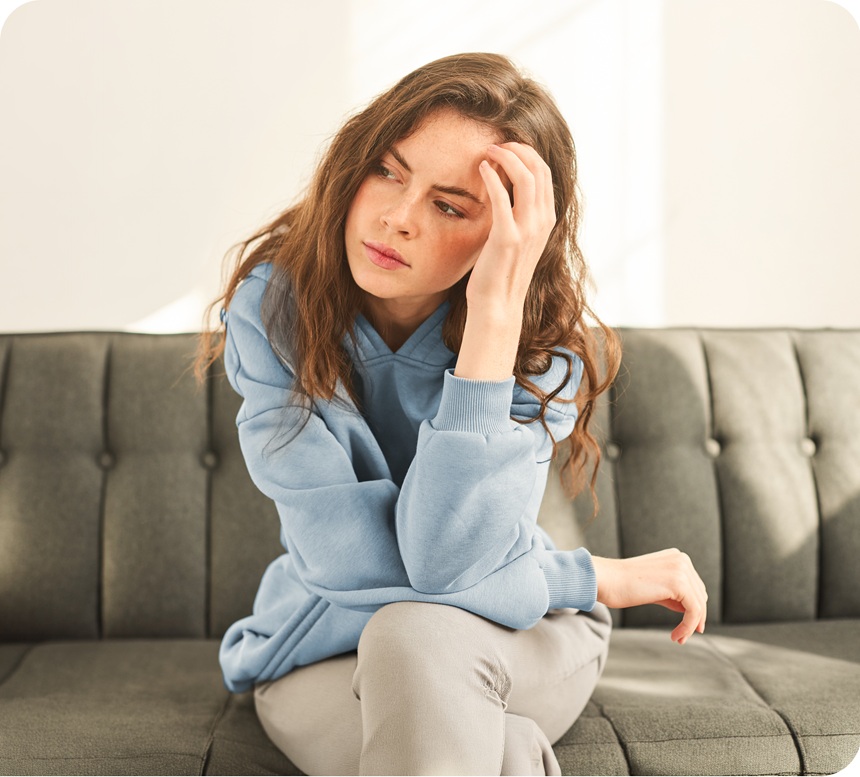 Woman looks concerned while holding hand to her forehead.