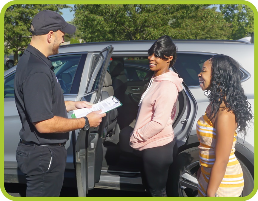 Man holds clipboard in front of car with a woman and her daughter