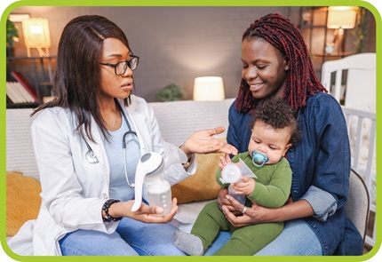 Woman doctor talks with mom as she holds her baby