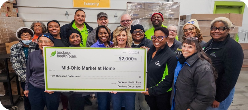 A group of Buckeye staff and Mid-Ohio Market at Home reps stand behind a large grant check.