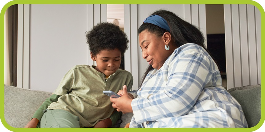 Woman looks at phone with her son while sitting on the couch